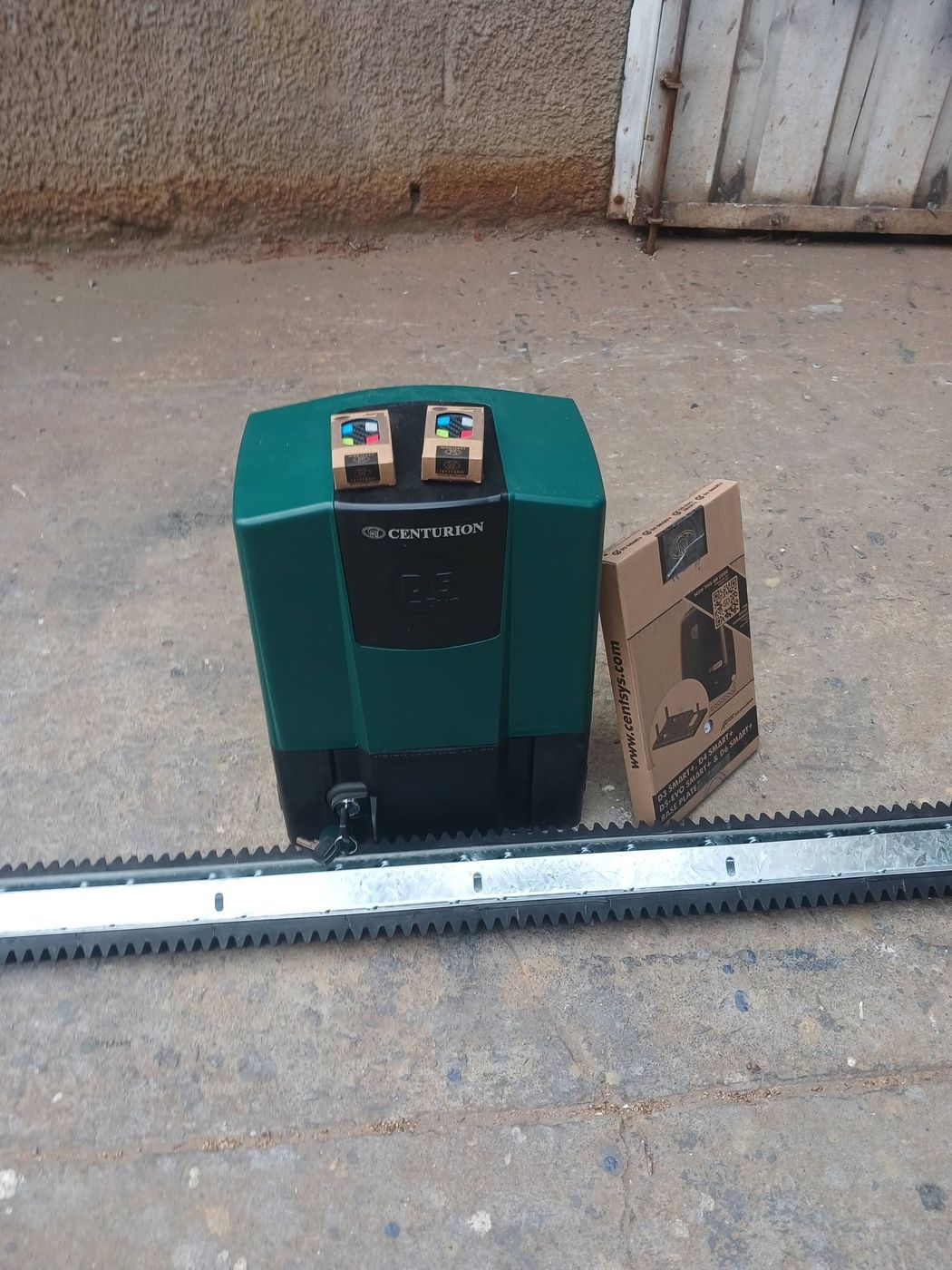 Centurion sliding gate motor with two remotes beside its drive rack