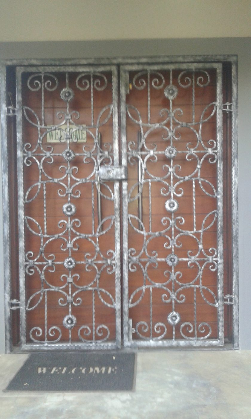 Ornate wrought-iron security doors with a scroll pattern over a front entrance