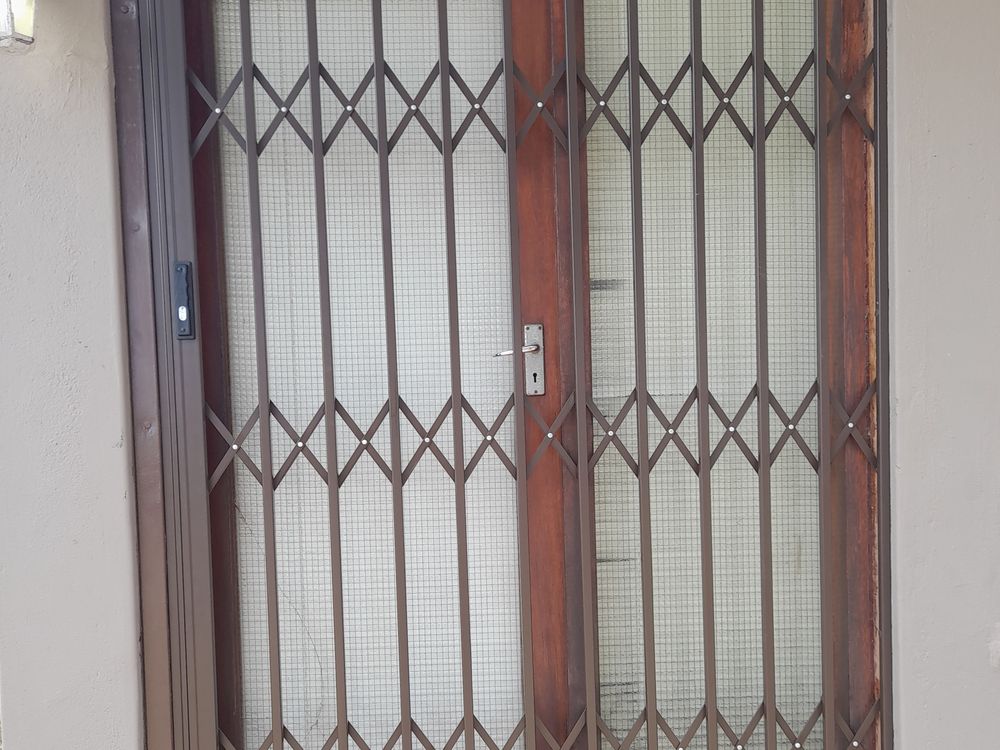 Retractable trellis security gate fitted over a wooden front door