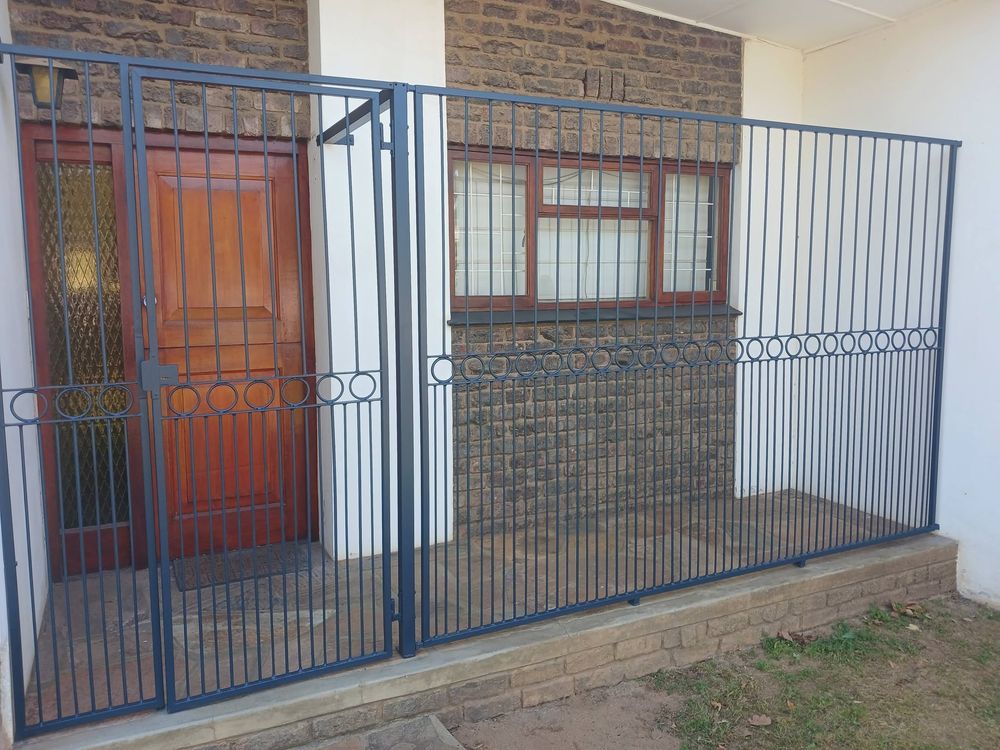 Blue-grey steel security gate and barrier enclosing a front entrance and window