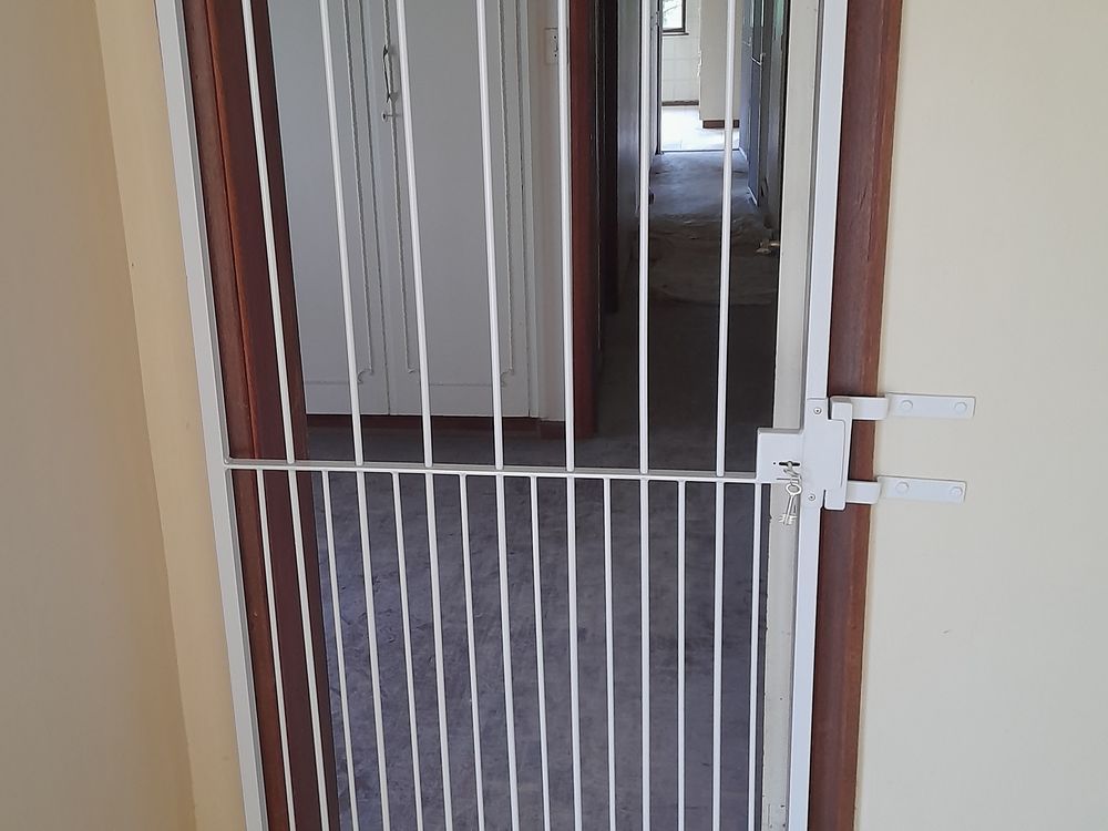 White steel security gate with a lock fitted inside a doorway