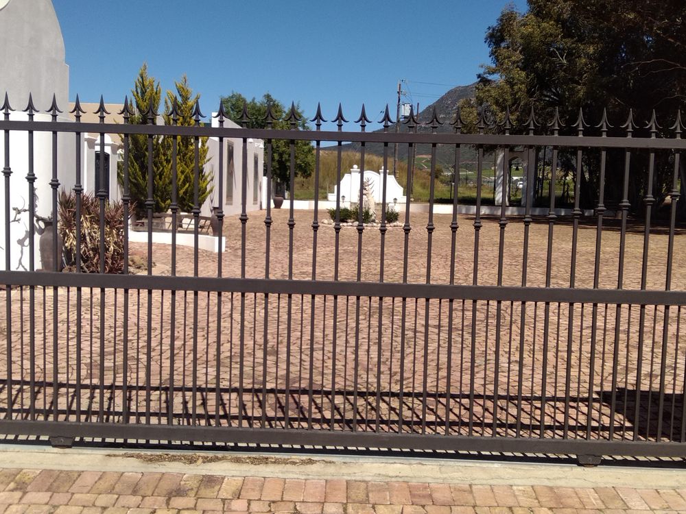 Black steel sliding gate with spear-topped bars across a driveway