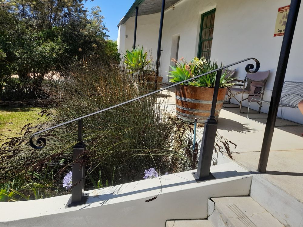 Black steel handrail with a scroll end beside a porch step