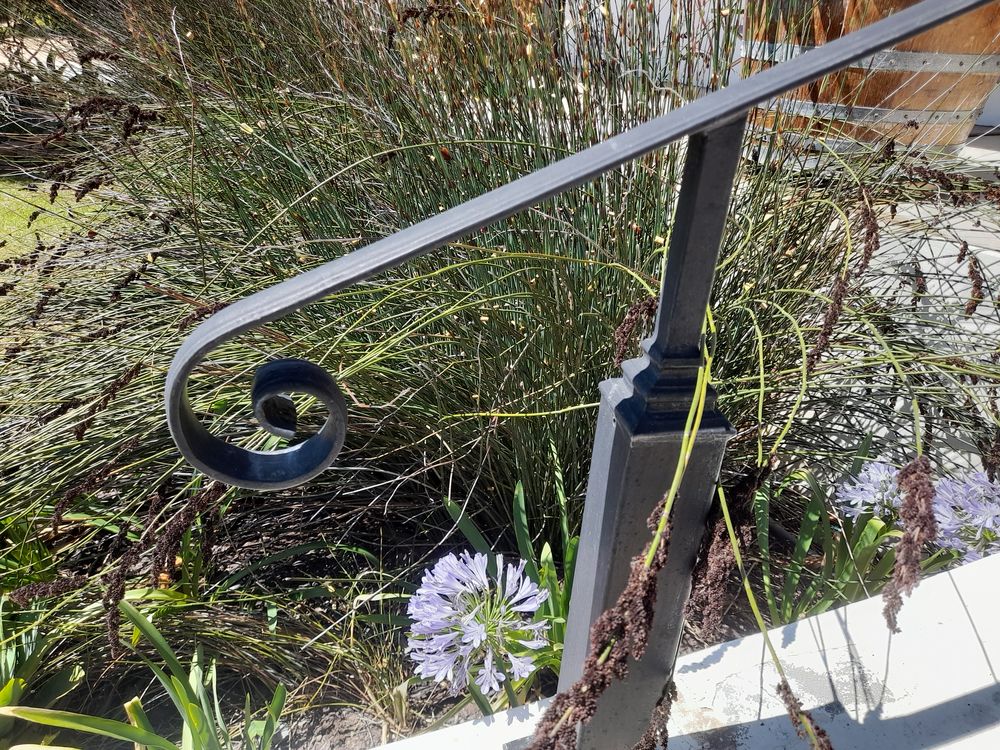 Close view of a steel handrail ending in a scroll on a square post