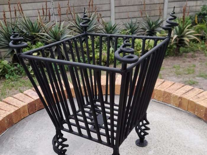 Black steel planter stand with spiral feet on a paved circle